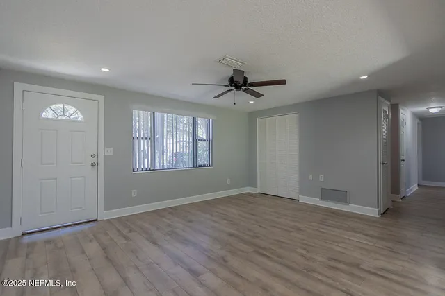 a view of an empty room with a window and wooden floor