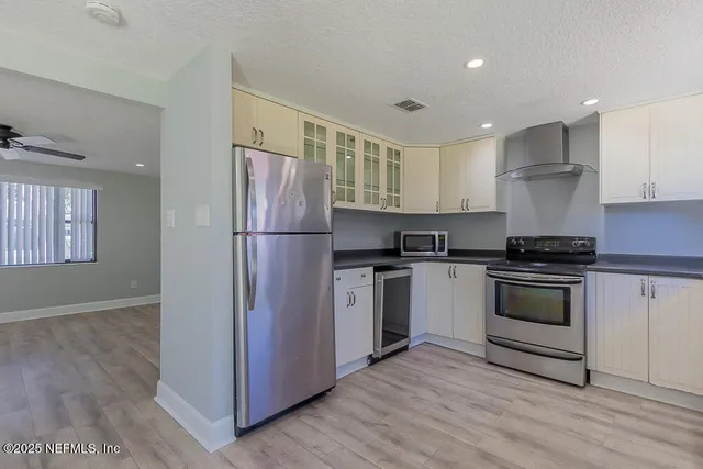 a kitchen with a refrigerator stove and white cabinets