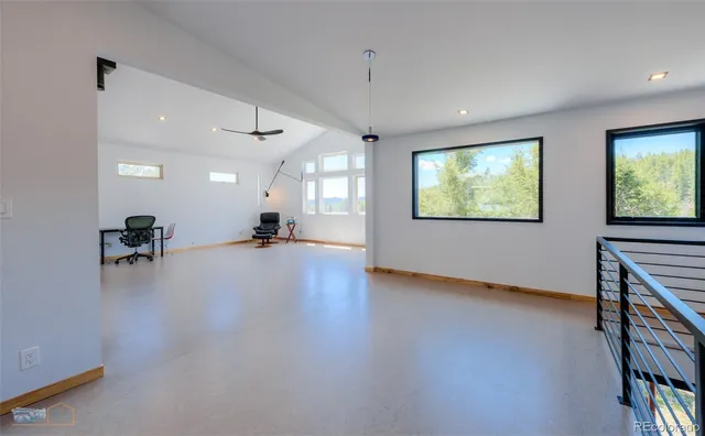 a view of an empty room with window and a kitchen