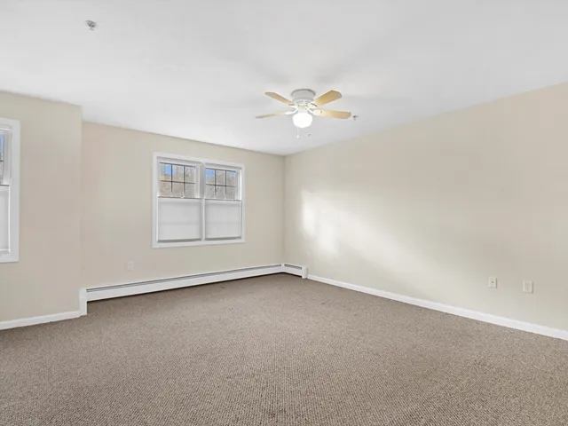 an empty room with windows and ceiling fan