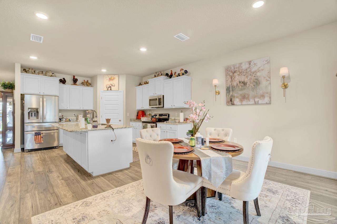 5364 Red Shoulder Road Pace, FL 32571 - Photo 33 of 46 a view of a dining room with furniture a rug and wooden floor