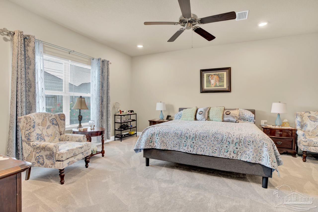 5364 Red Shoulder Road Pace, FL 32571 - Photo 34 of 46 a spacious bedroom with a bed a couch and a chandelier
