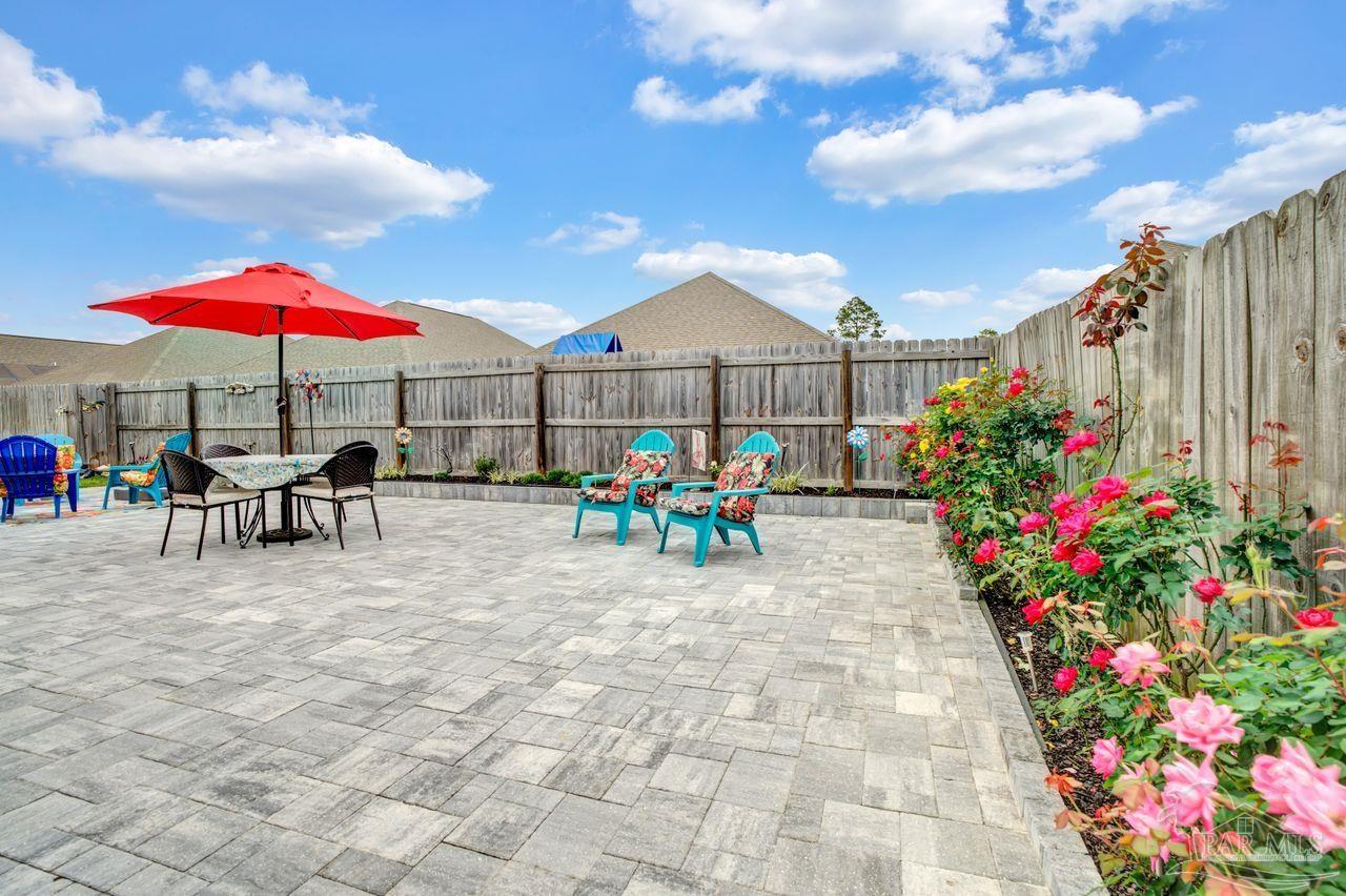 5364 Red Shoulder Road Pace, FL 32571 - Photo 40 of 46 a view of a patio with a table and chairs under an umbrella