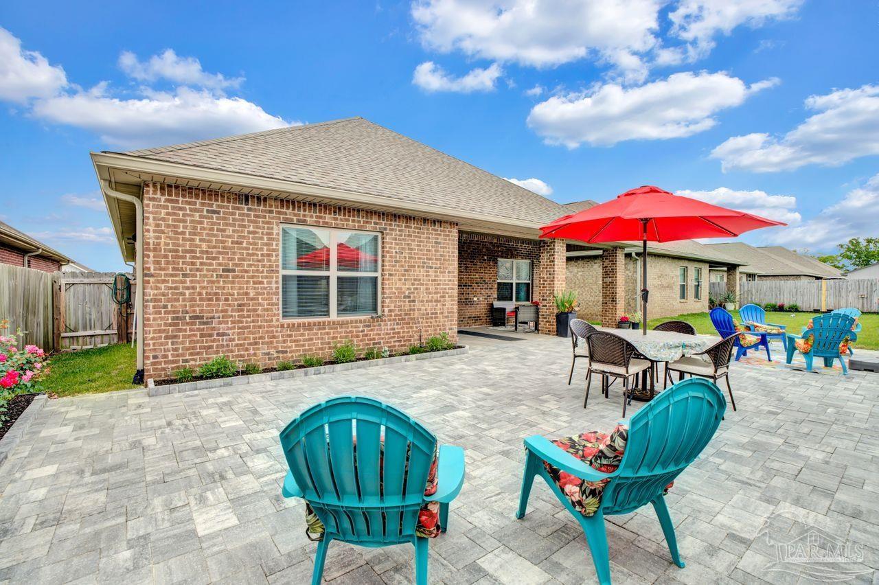 5364 Red Shoulder Road Pace, FL 32571 - Photo 41 of 46 a patio with a table and chairs under an umbrella