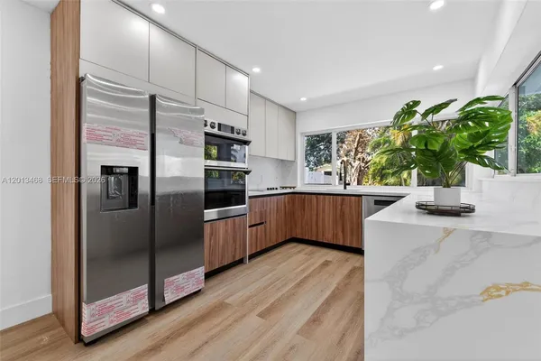a kitchen with stainless steel appliances kitchen island granite countertop a refrigerator a sink and a stove