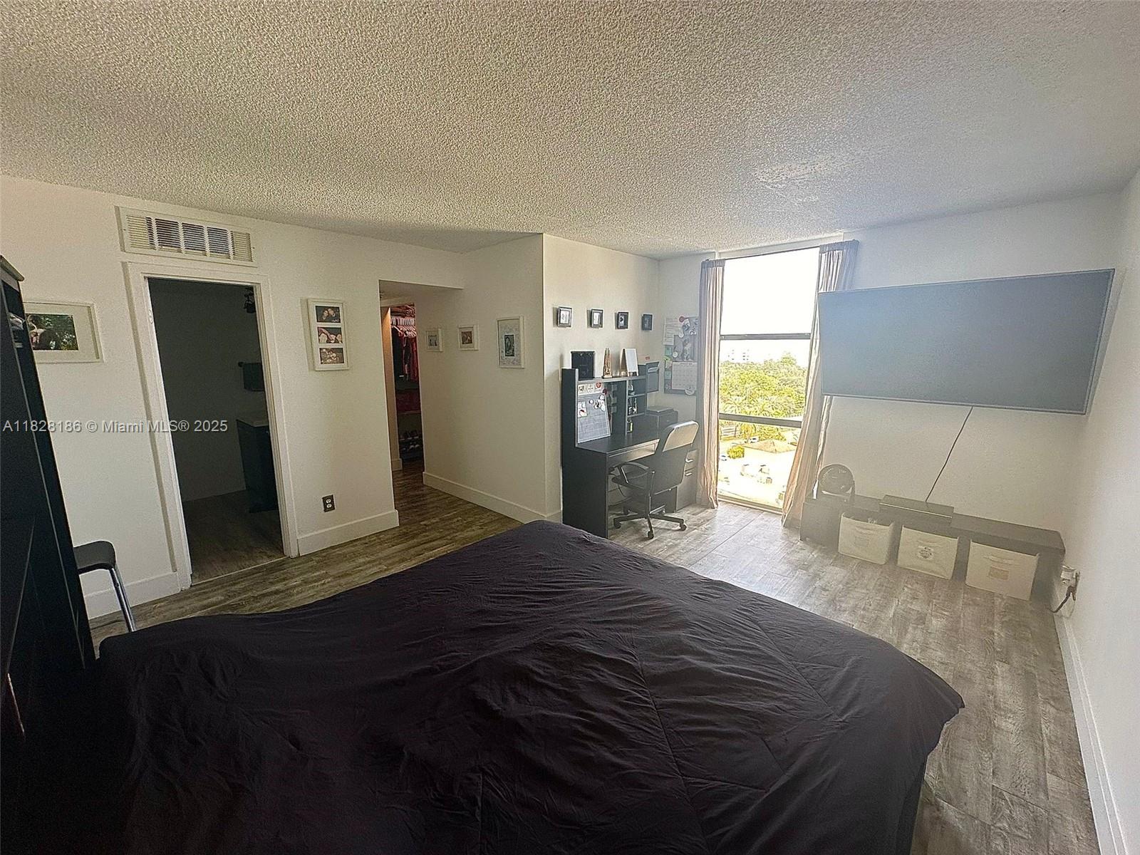 13499 Biscayne Boulevard, Unit 1013 North Miami, FL 33181 - Photo 17 of 25 a bedroom with a bed and wooden floor