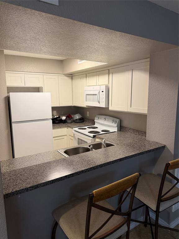 9805 Walnut Street, Unit C102 Dallas, TX 75243 - Photo 2 of 15 a kitchen with a sink a stove a refrigerator and white cabinets