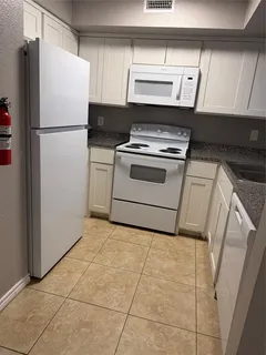 a white refrigerator freezer and a stove sitting inside of a kitchen