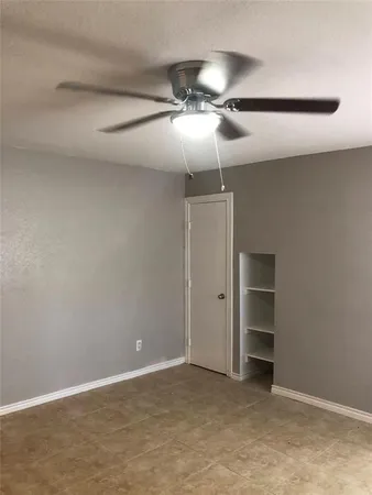 an empty room with closet and a chandelier fan