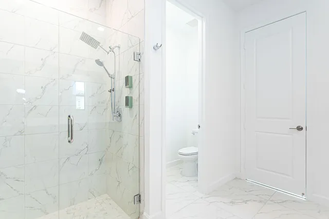 a bathroom with a granite countertop shower and toilet