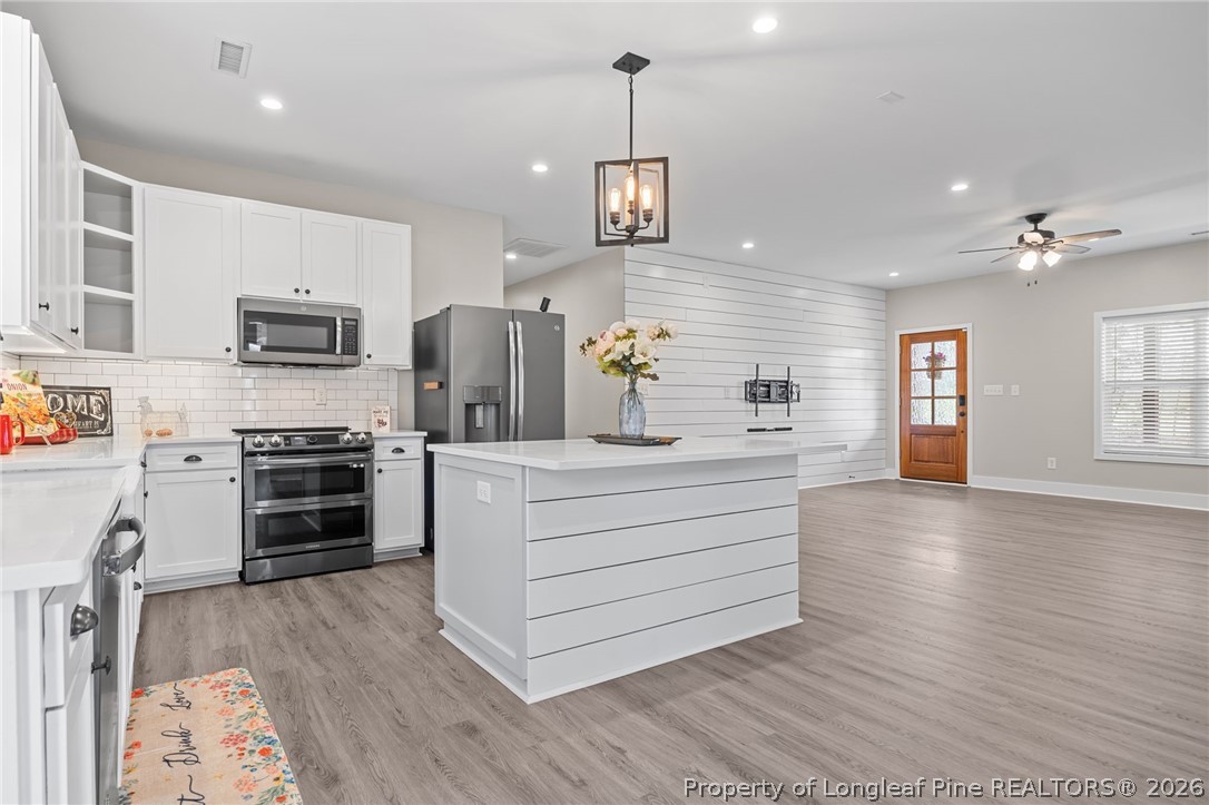 432 Pearidge Road Willow Spring, NC 27592 - Photo 8 of 47 a kitchen with stainless steel appliances kitchen island wooden floor and chandelier
