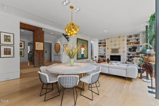 a view of a dining room and livingroom with furniture wooden floor a chandelier