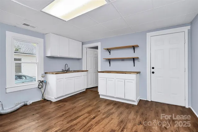 a kitchen with wooden floors and white cabinets