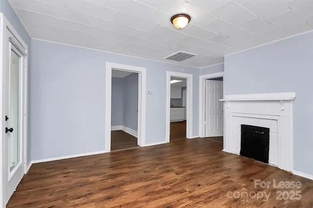a view of empty room with wooden floor and fireplace