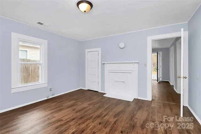 an empty room with wooden floor cabinet and windows