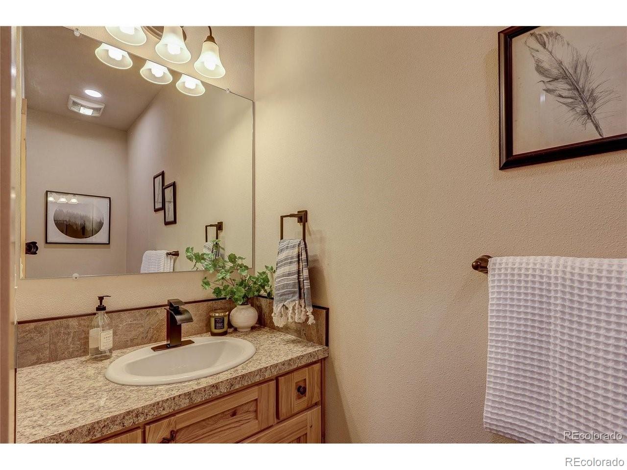 18298 Romar Rnch Road Carr, CO 80612 - Photo 12 of 49 a bathroom with a granite countertop sink a mirror and vanity