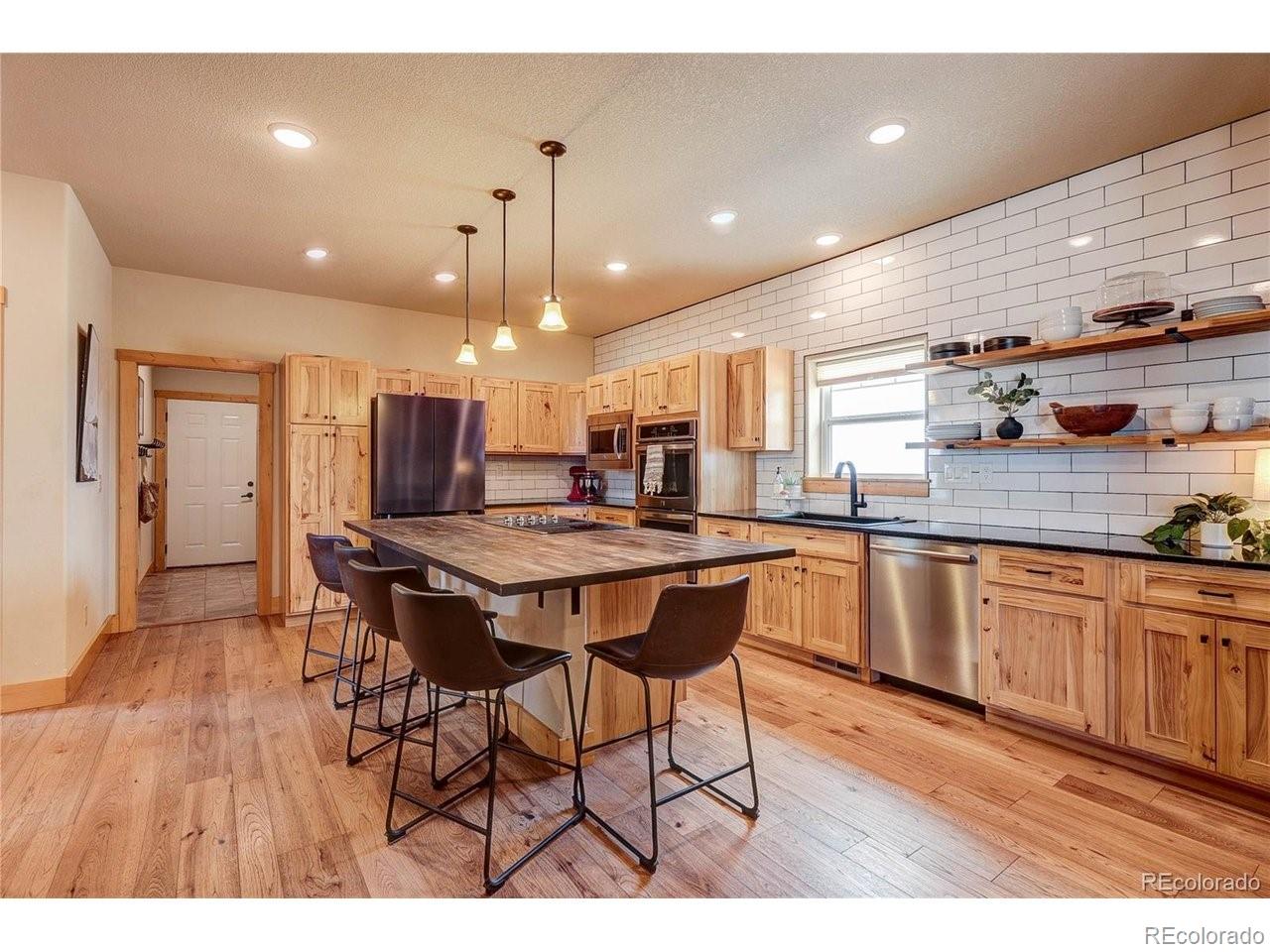 18298 Romar Rnch Road Carr, CO 80612 - Photo 16 of 49 a kitchen with stainless steel appliances granite countertop a kitchen island a stove a sink a refrigerator and a microwave