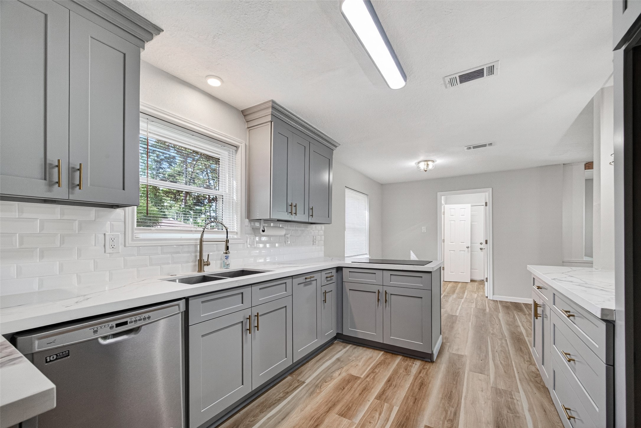 25503 Foxbriar Lane Spring, TX 77373 - Photo 5 of 45 a kitchen with a sink dishwasher a stove and white cabinets with wooden floor