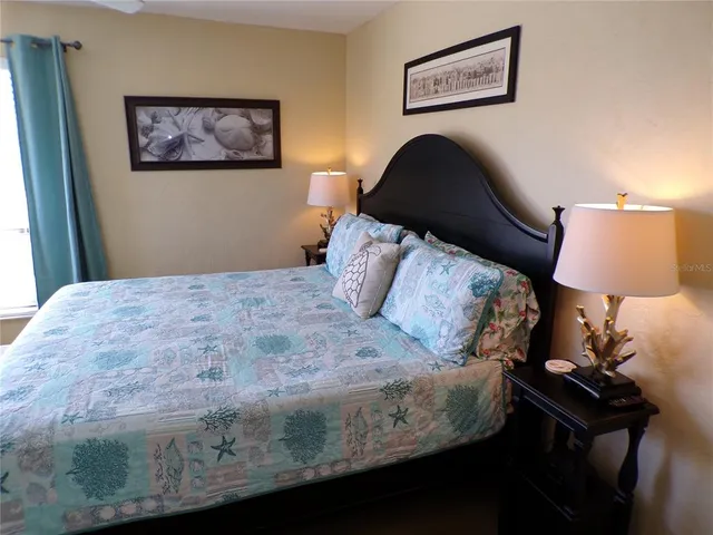 a bedroom with a bed and a lamp on dresser