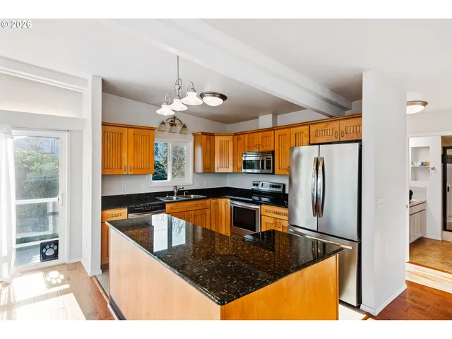 a kitchen with stainless steel appliances granite countertop a sink a stove and a refrigerator