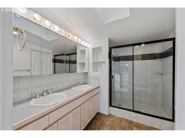 a bathroom with a double vanity sink mirror and shower