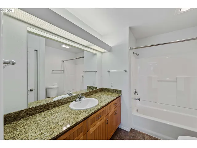 a bathroom with a granite countertop sink tub shower and a mirror