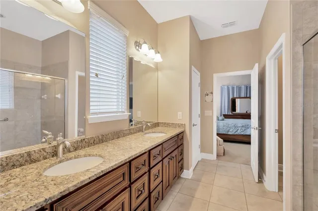 a bathroom with a granite countertop double vanity sink and a mirror