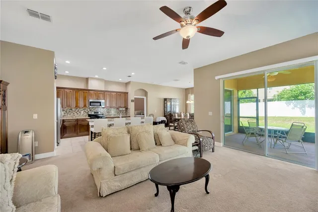 a living room with furniture and a large window with kitchen view