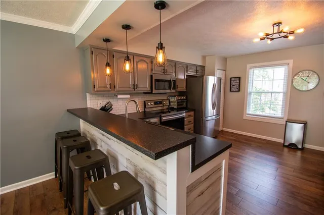 a kitchen with stainless steel appliances a stove a refrigerator and a refrigerator with wooden floor