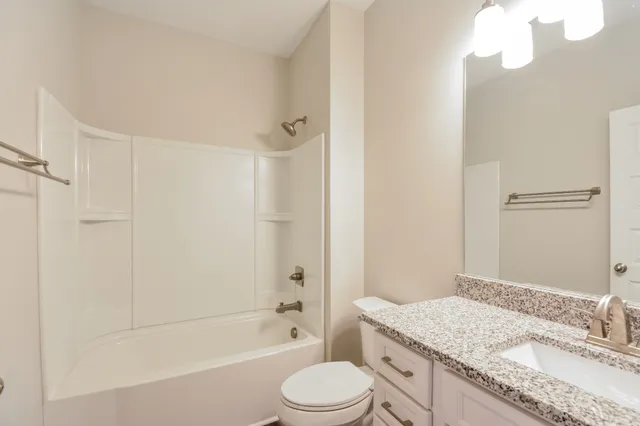 a bathroom with a granite countertop sink toilet tub and shower