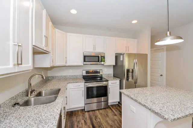 a kitchen with kitchen island granite countertop a sink stove and refrigerator