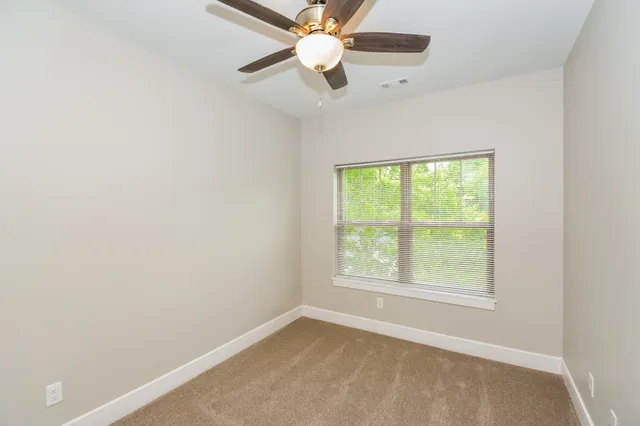 an empty room with a window and a fan