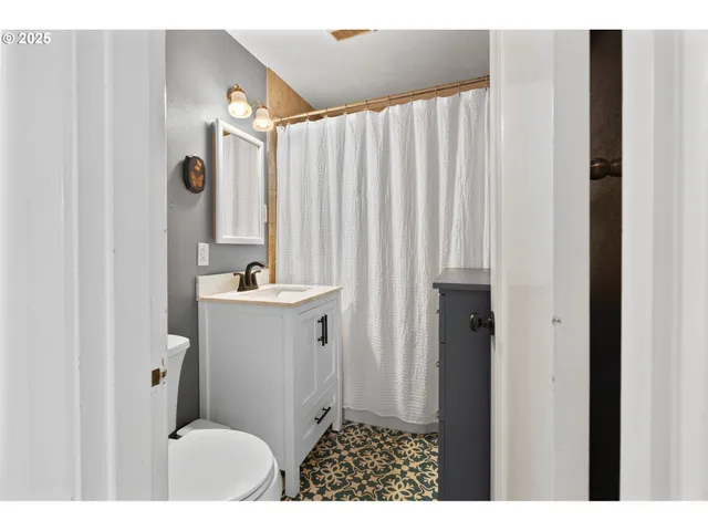 a bathroom with a sink a toilet a mirror and shower