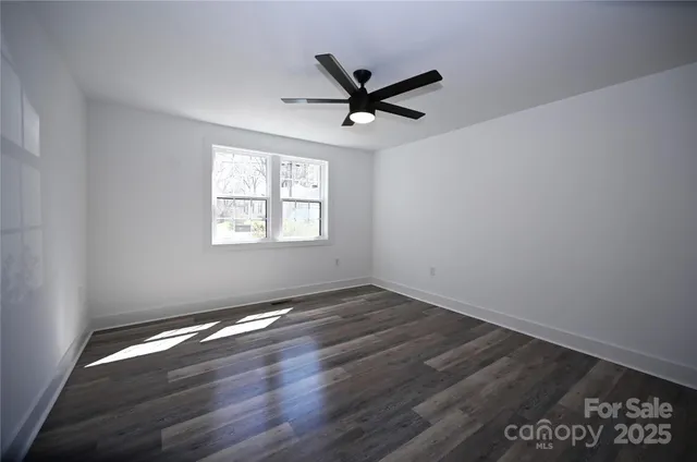 an empty room with wooden floor fan and windows