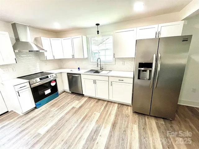 a kitchen with stainless steel appliances granite countertop a refrigerator a sink a stove and oven with wooden floor