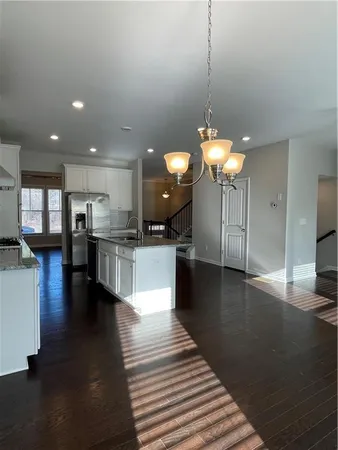a kitchen with stainless steel appliances kitchen island granite countertop a stove top oven a dining table and chairs with wooden floor