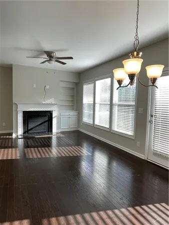 an empty room with wooden floor fireplace and windows