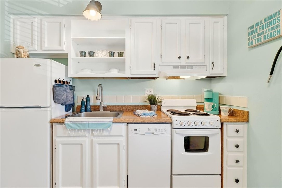 622 Beach Access Road, Unit 216 Port Aransas, TX 78373 - Photo 11 of 32 a kitchen with kitchen island a white cabinets and white appliances