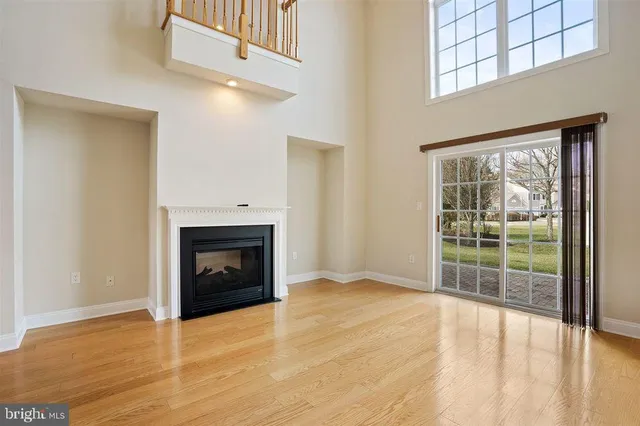 an empty room with wooden floor fireplace and windows