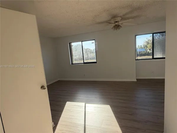 a view of an empty room with wooden floor and a window