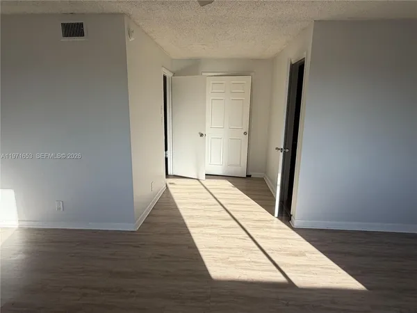 a view of a room with wooden floor and white walls