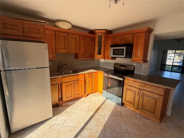 a kitchen with granite countertop a refrigerator and a stove top oven