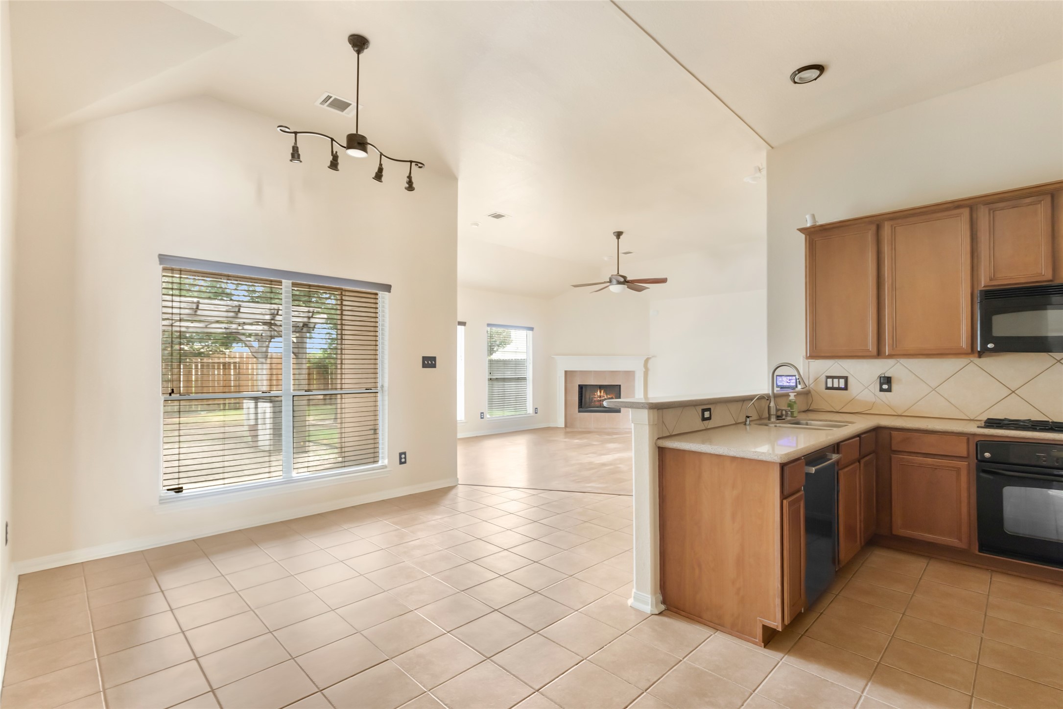 24706 East Burnaby Circle Spring, TX 77373 - Photo 13 of 34 Bright and open living space featuring a cozy fireplace, modern kitchen with sleek appliances, and large windows offering abundant natural light.
