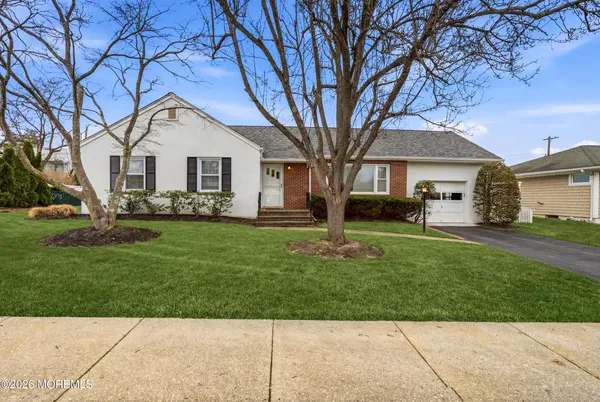 a front view of a house with a garden and trees