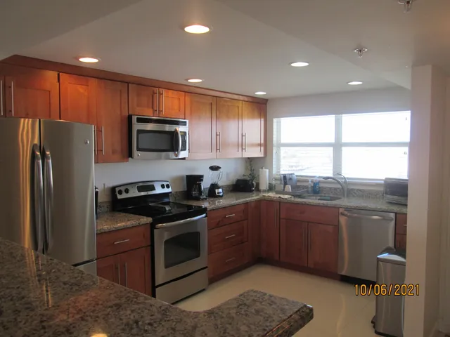 a kitchen with stainless steel appliances granite countertop a stove a sink dishwasher a refrigerator and a microwave