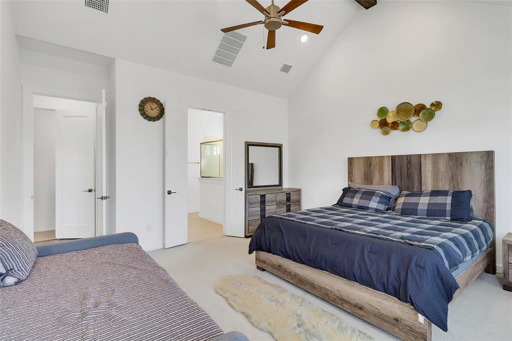 1241 Lupine Road Prosper, TX 75078 - Photo 20 of 38 Bedroom featuring a vaulted ceiling with a ceiling fan, light-toned carpet flooring, two paneled doors, and a partial view into an adjacent bathroom