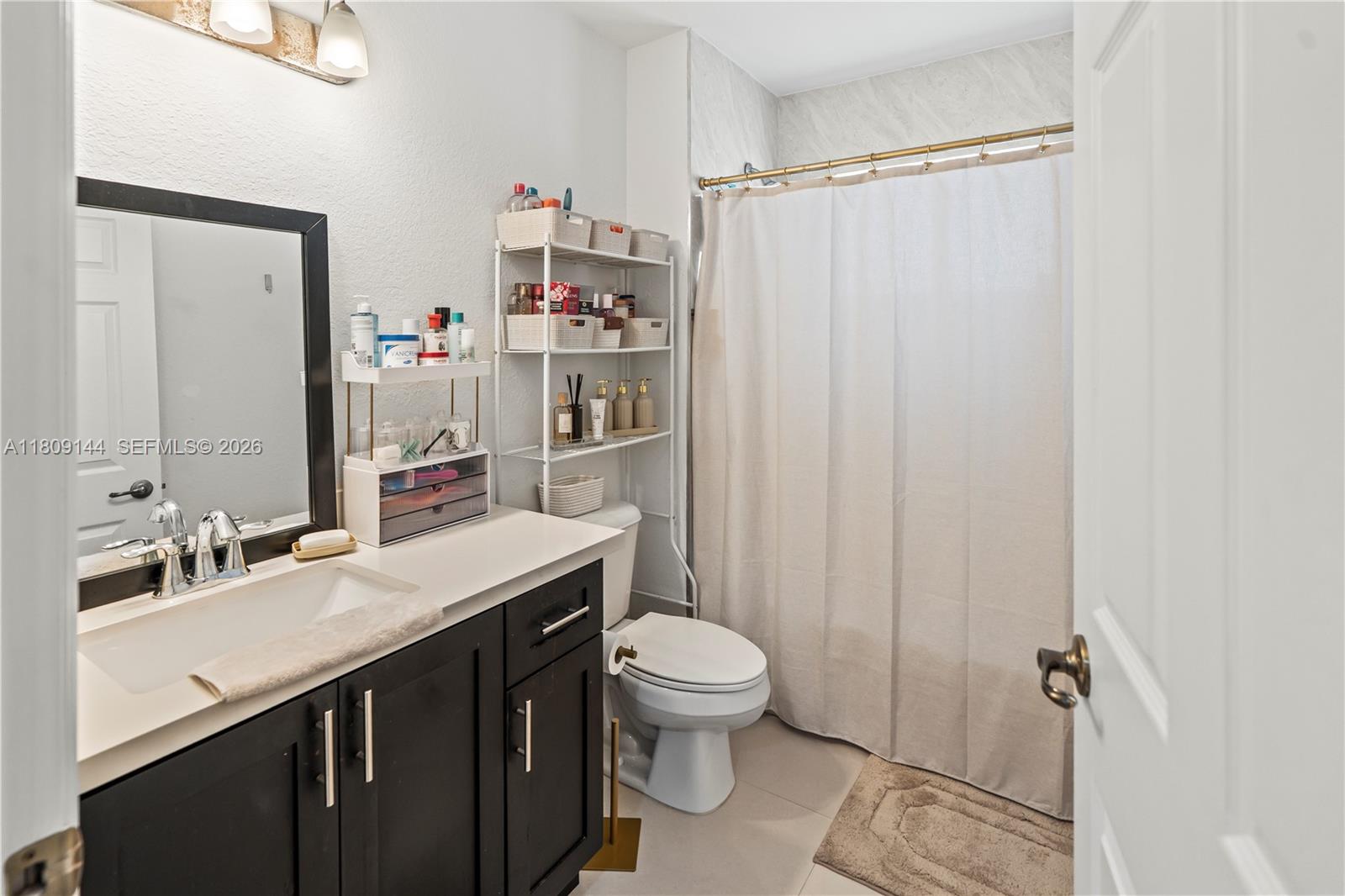 3801 Southwest 149th Avenue Miami, FL 33185 - Photo 22 of 41 a bathroom with a sink a toilet a mirror and shower curtain