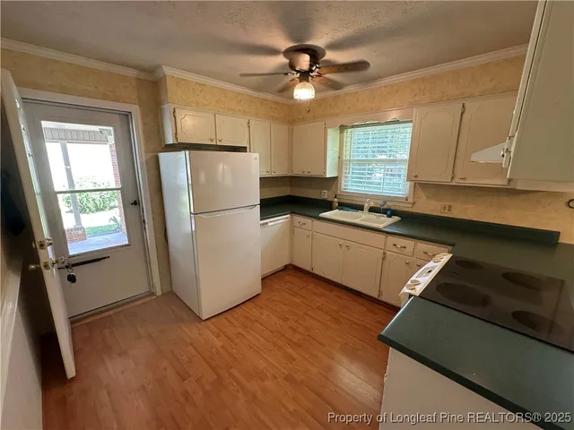 a kitchen with granite countertop a refrigerator a sink a stove a microwave and cabinets