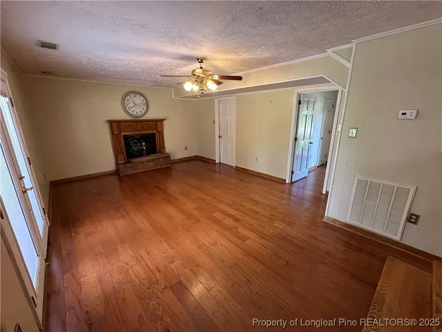 an empty room with wooden floor fireplace and fan