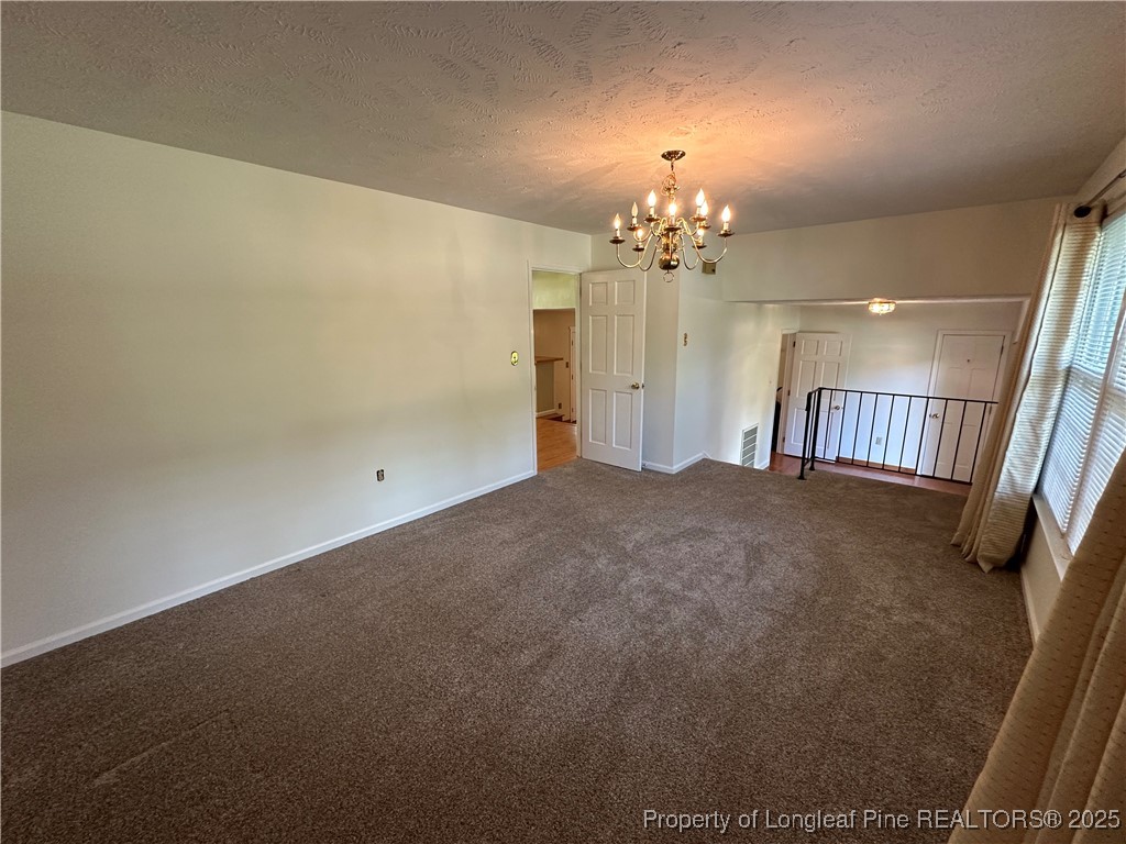 3120 Hampstead Road Lumberton, NC 28360 - Photo 24 of 30 an empty room with a chandelier fan and windows
